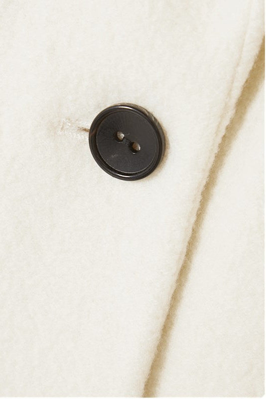 Détail du bouton et de la texture du manteau blanc